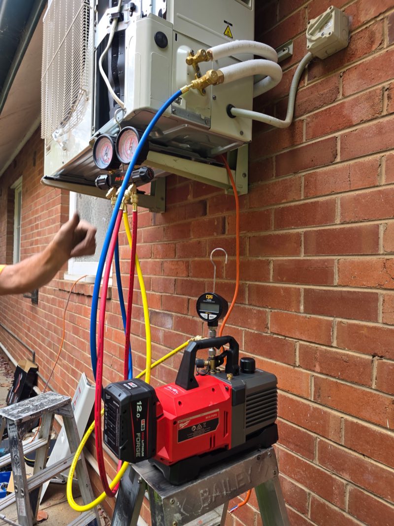 H1 Electrical & Air technician servicing and commissioning a split system with manifold gauges in Cowra