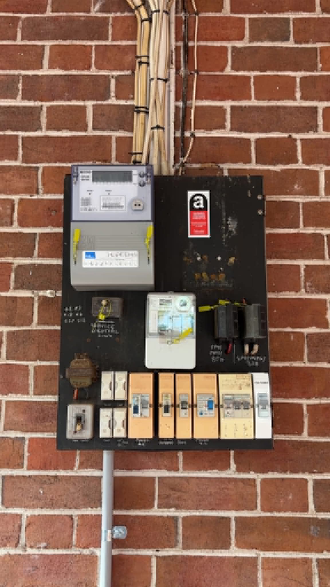 Old surface-mounted switchboard with ceramic fuses and mixed breakers before upgrade by H1 Electrical & Air