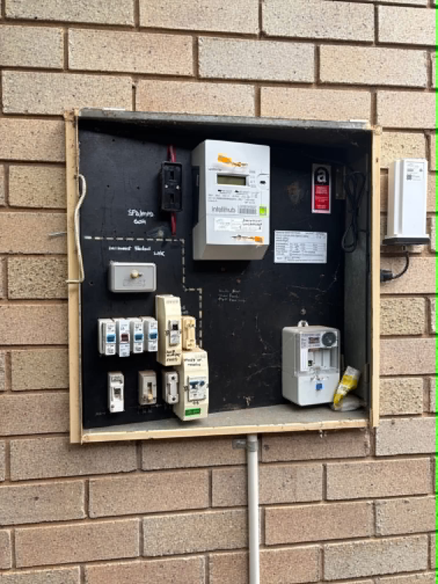 Old recessed meter box with an untidy mix of fuses and breakers before upgrade by H1 Electrical & Air